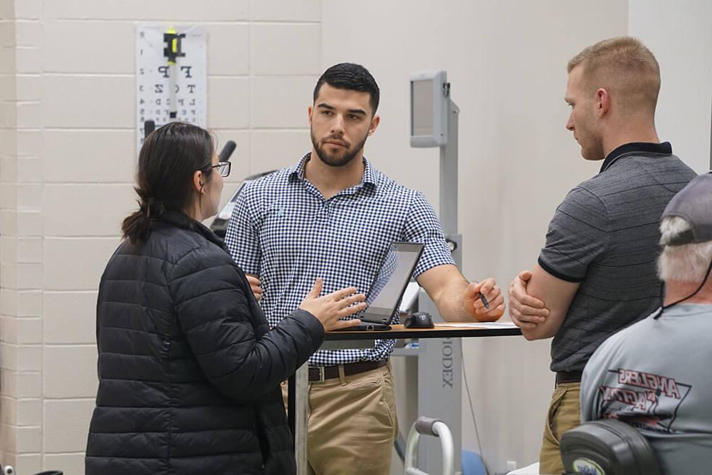 Physical therapy students in discussion around laptop